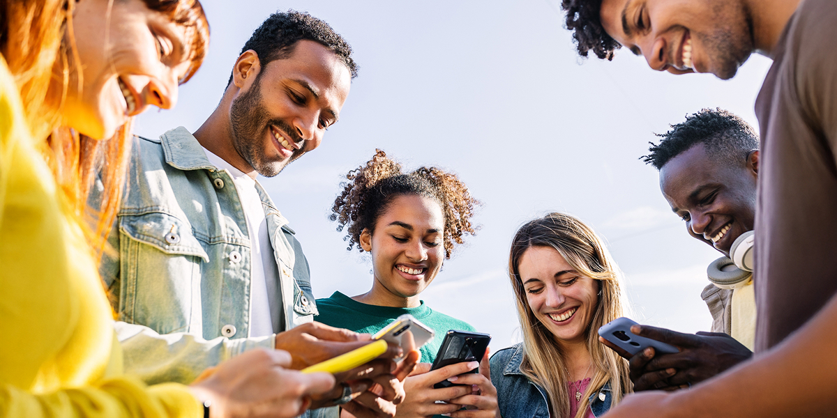 Young creators exchanging ideas and content on mobile devices, reflecting shared energy, technology access, and the collaborative spirit at the heart of a globally connected platform.