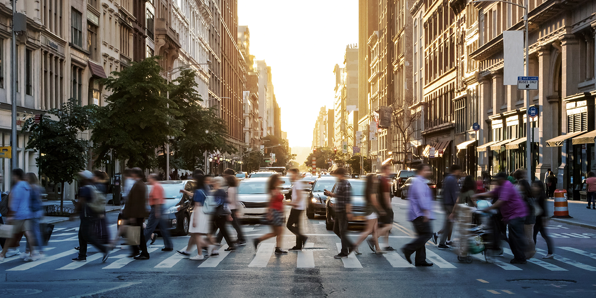 Street‑level motion blur of people walking in synchrony, evoking anonymized momentum, shared direction, and the quiet choreography of global connection.